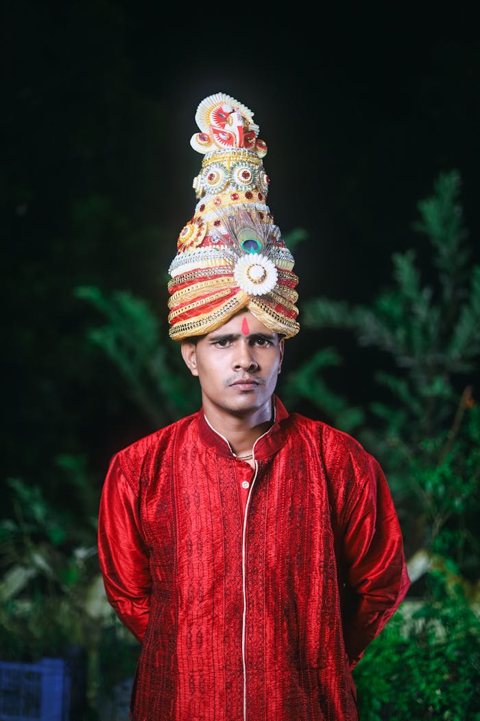 Portrait of a man in a red traditional Indian outfit with a decorative wedding pagdi.